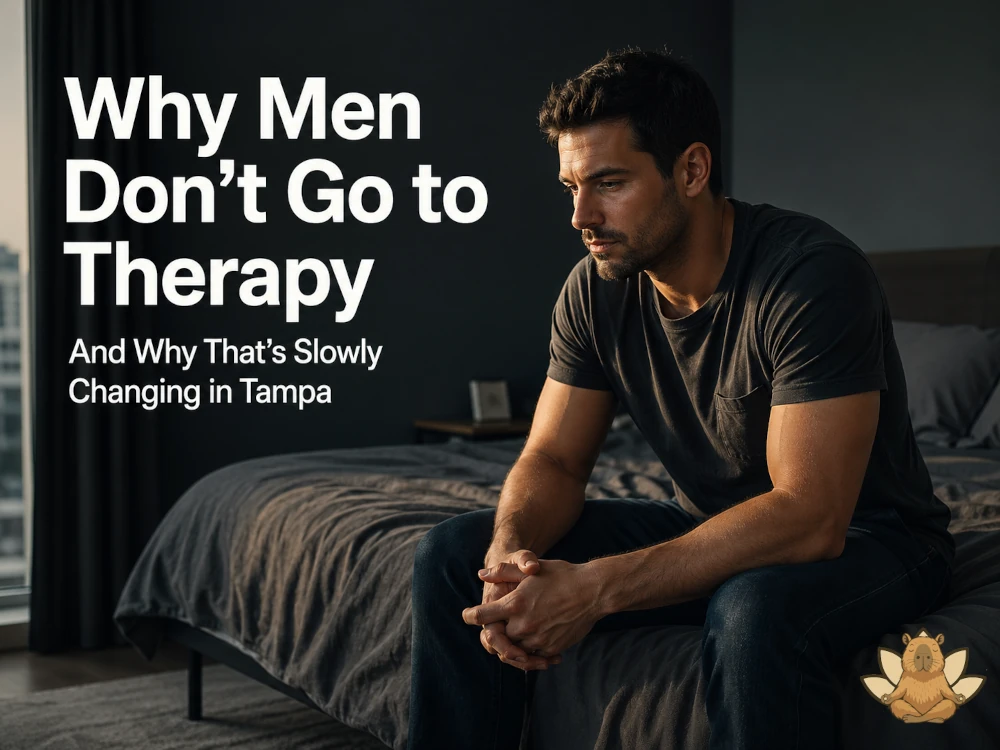 Man sitting on edge of bed in dimly lit room reflecting on why men avoid therapy in Tampa